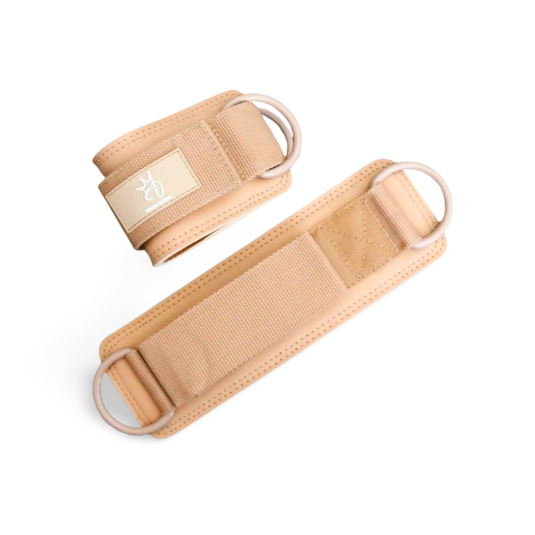 Pair of beige anklestraps with metal rings on a white background