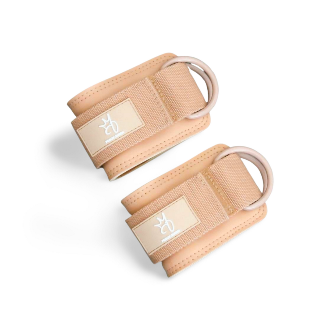 Pair of beige ankle straps with brand logo on a white background
