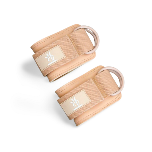 Pair of beige ankle straps with brand logo on a white background
