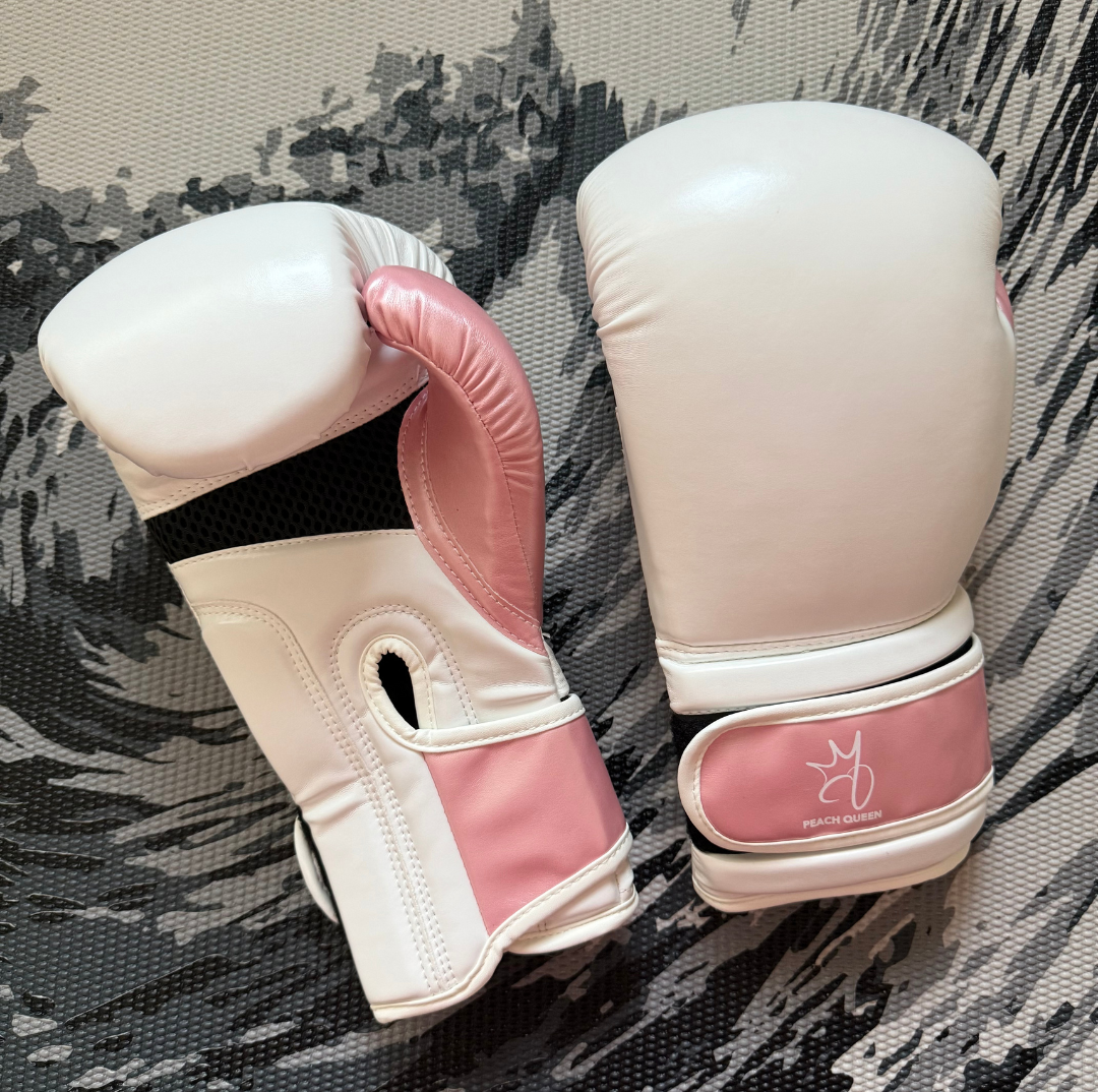 Pair of pink and white boxing gloves on a textured surface